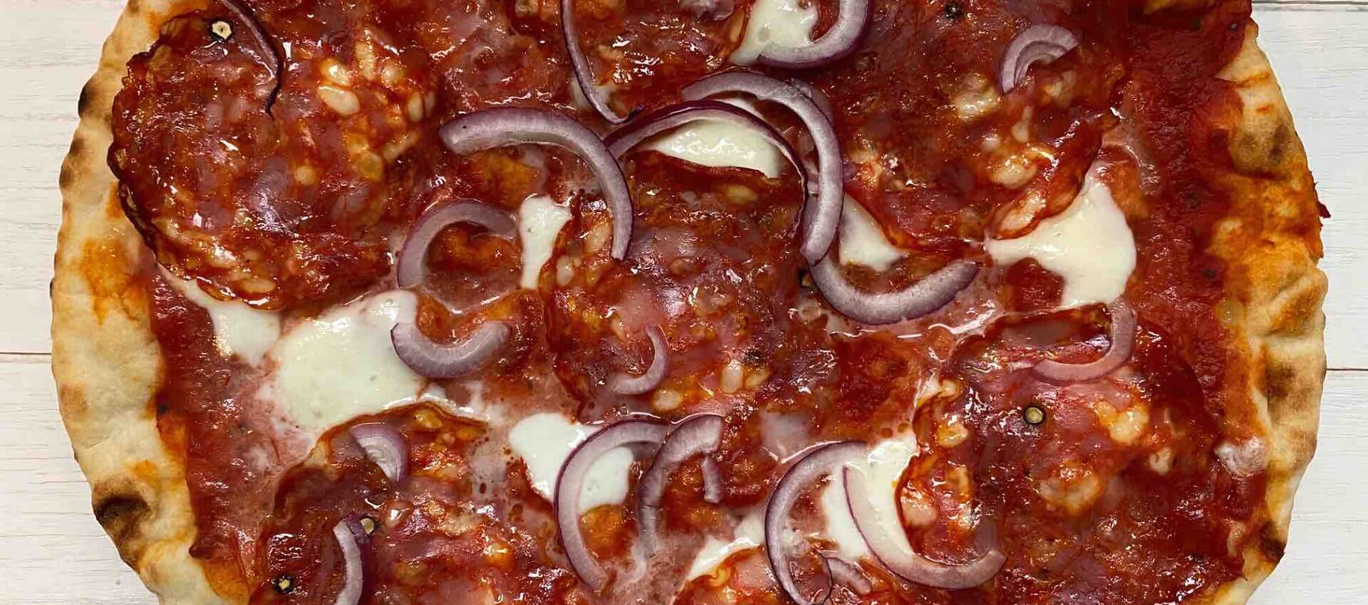 Pizza met pikante salami en rode ui