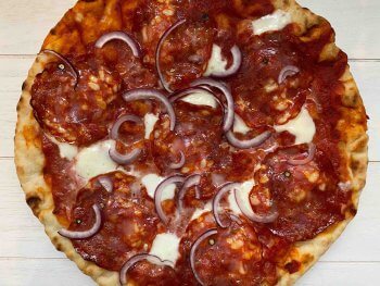 Pizza met pikante salami en rode ui